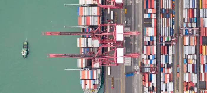 Bovenaanzicht van een containerschip aan de kade, met kranen en gestapelde containers