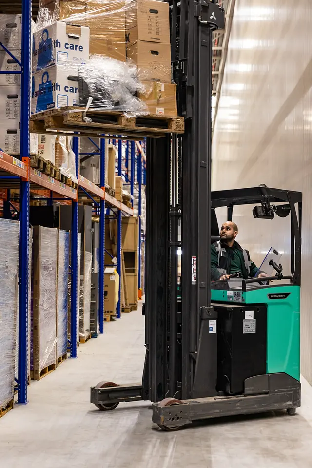Reachtruck plaatst een pallet hoog in de stelling van het warehouse